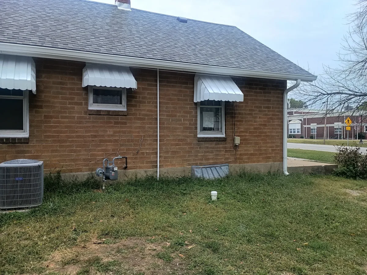 brick home with refinished white awnings and trim