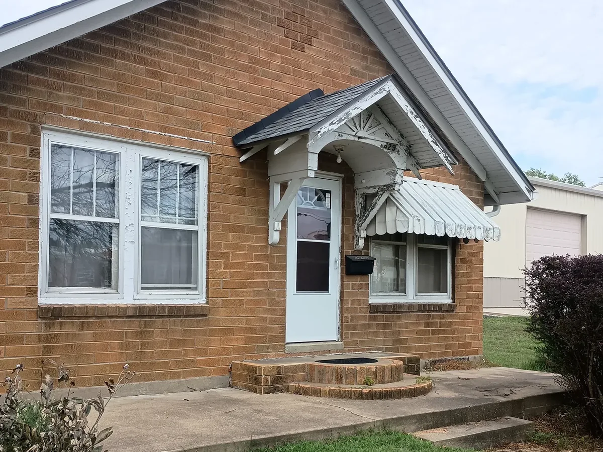 brick home entry with failing green awning