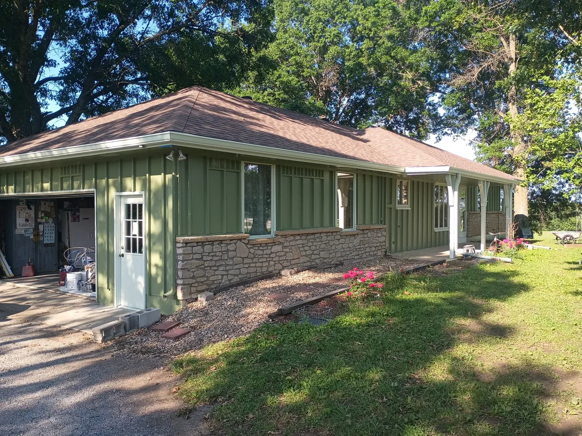 ranch home repainted deep green over stone base